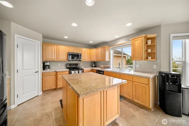 a kitchen with stainless steel appliances granite countertop a refrigerator a sink dishwasher a stove and white countertops with wooden floor