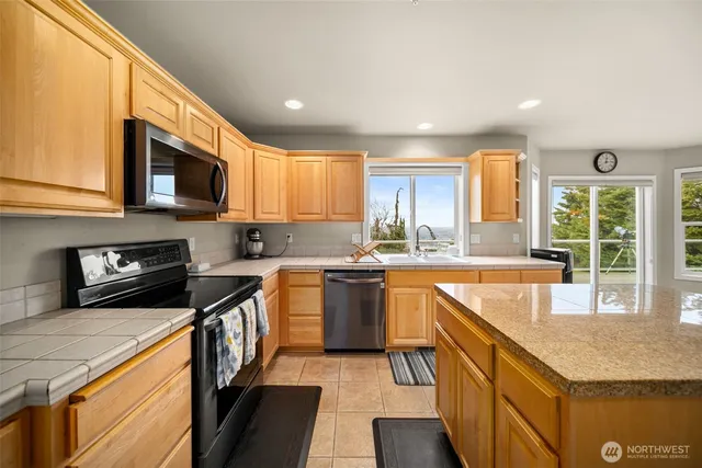 a kitchen with stainless steel appliances granite countertop wooden cabinets a stove a sink and a microwave