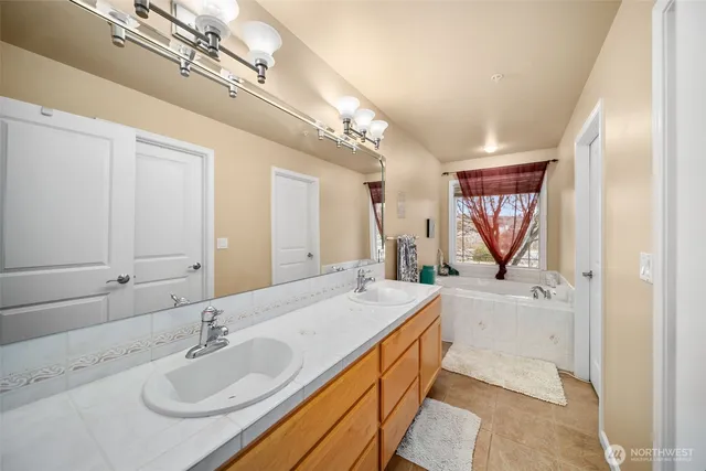 a spacious bathroom with a granite countertop sink a large mirror and a bathtub