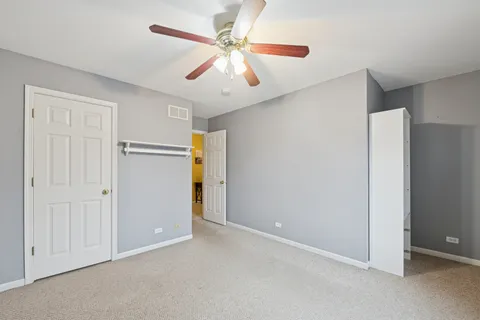 an empty room with closet and a ceiling fan