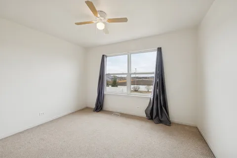 an empty room with a ceiling fan and window