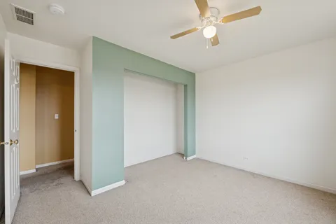 an empty room with closet and a chandelier fan