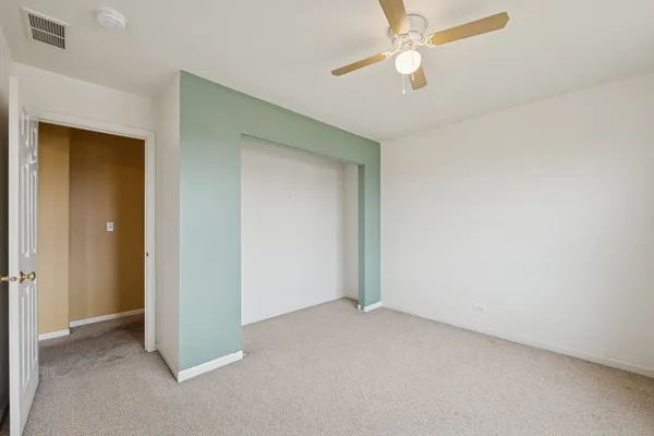 an empty room with closet and a chandelier fan