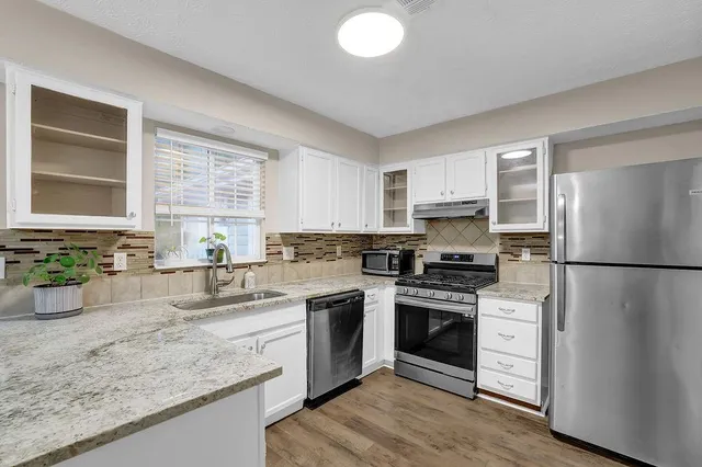 a kitchen with a sink white cabinets and stainless steel appliances
