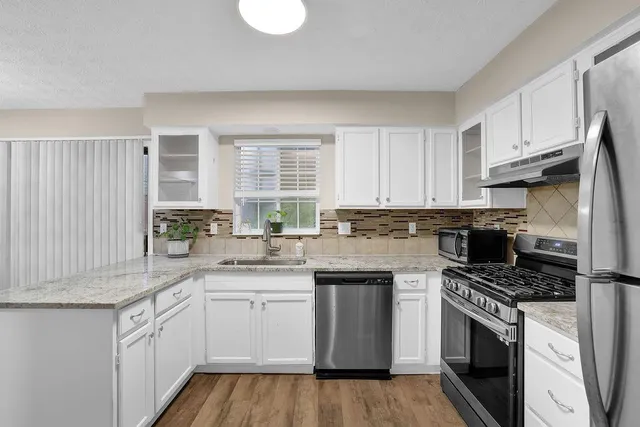 a kitchen with cabinets appliances a sink and a window