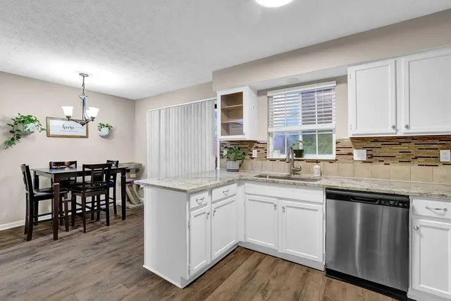 a kitchen with lots of white cabinets appliances and dining table