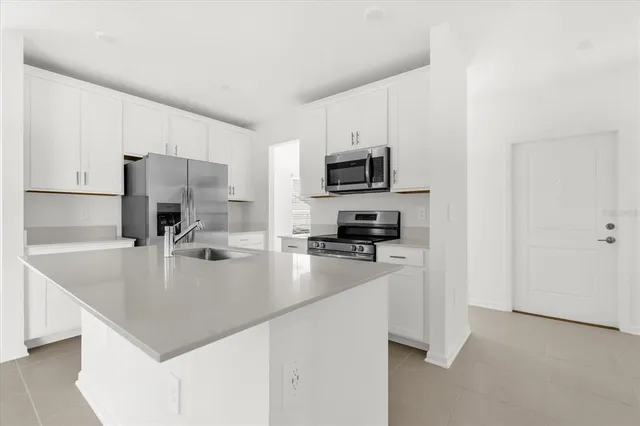 a kitchen with kitchen island a white counter top space cabinets and stainless steel appliances