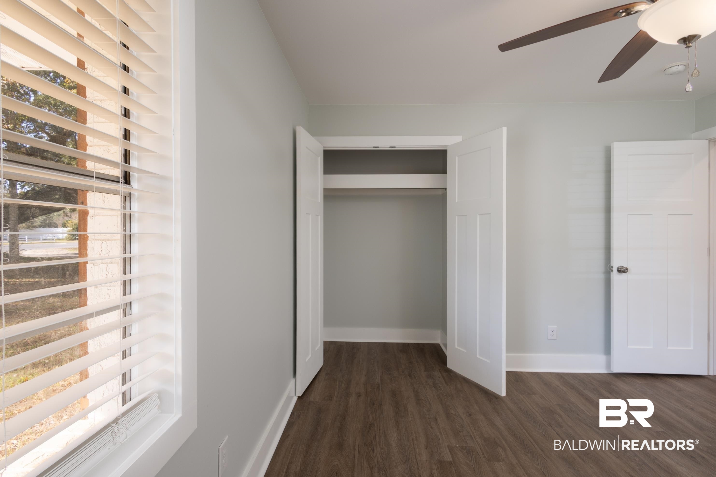 18267 Highway 98 Foley, AL 36535 - Photo 15 of 26 Unfurnished bedroom with multiple windows, dark wood-style floors, a ceiling fan, and a closet