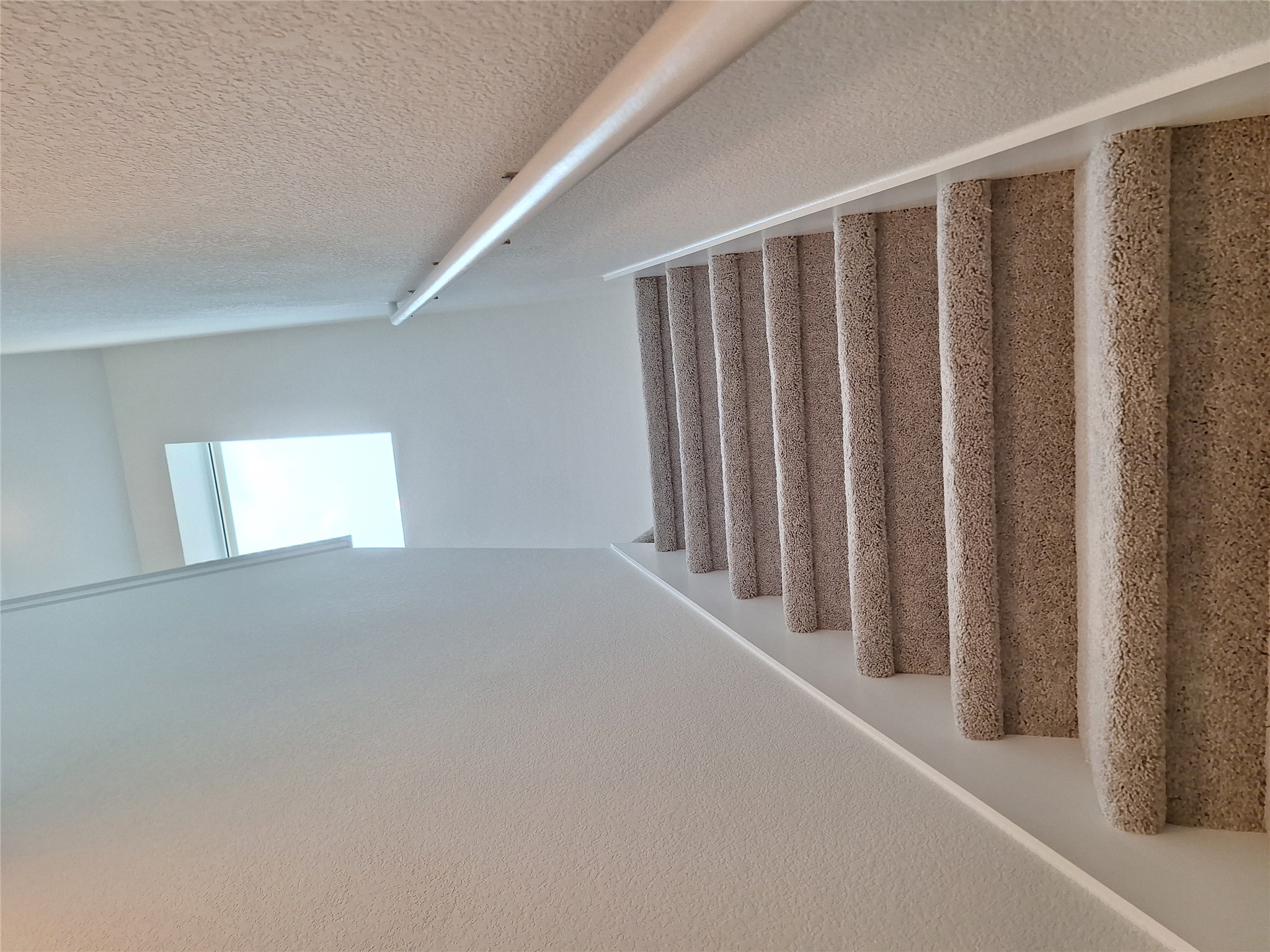 18001 Prairie Falcon Way Pflugerville, TX 78660 - Photo 11 of 38 Carpeted staircase featuring a light-colored railing and a window positioned at the landing