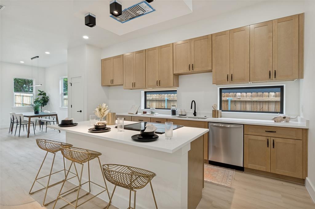 1143 Riverwood Road Dallas, TX 75217 - Photo 2 of 24 Modern kitchen featuring light wood-finish cabinetry, stainless steel appliances, and a central island with a quartz-finish countertop