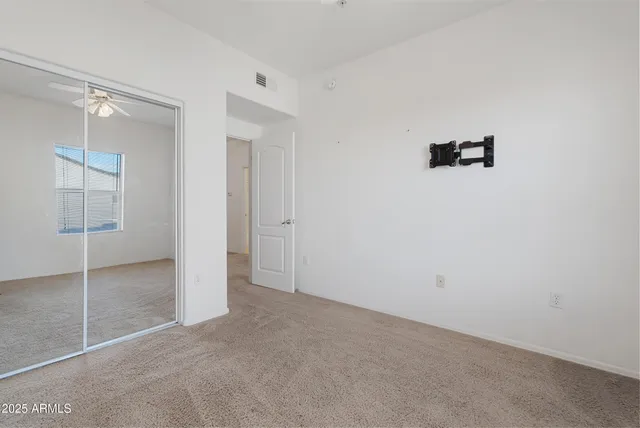 an empty room with a chandelier fan and window