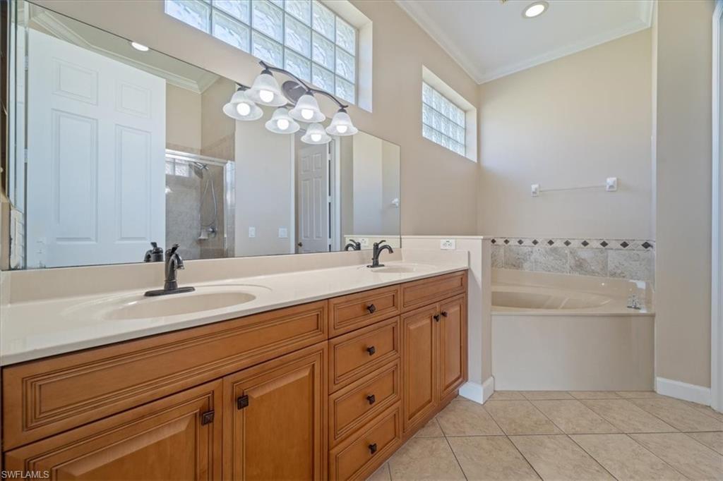 3343 Sandpiper Way Naples, FL 34109 - Photo 11 of 31 Bathroom with tile patterned floors, vanity, crown molding, and plus walk in shower