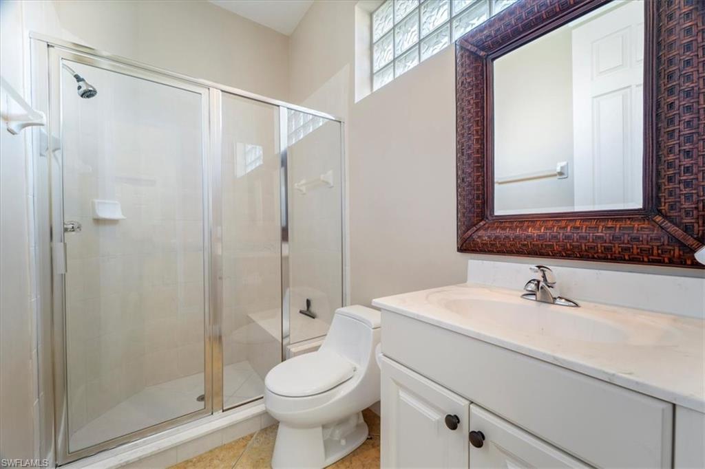 3343 Sandpiper Way Naples, FL 34109 - Photo 15 of 31 Bathroom featuring tile patterned flooring, a shower with door, vanity, and toilet