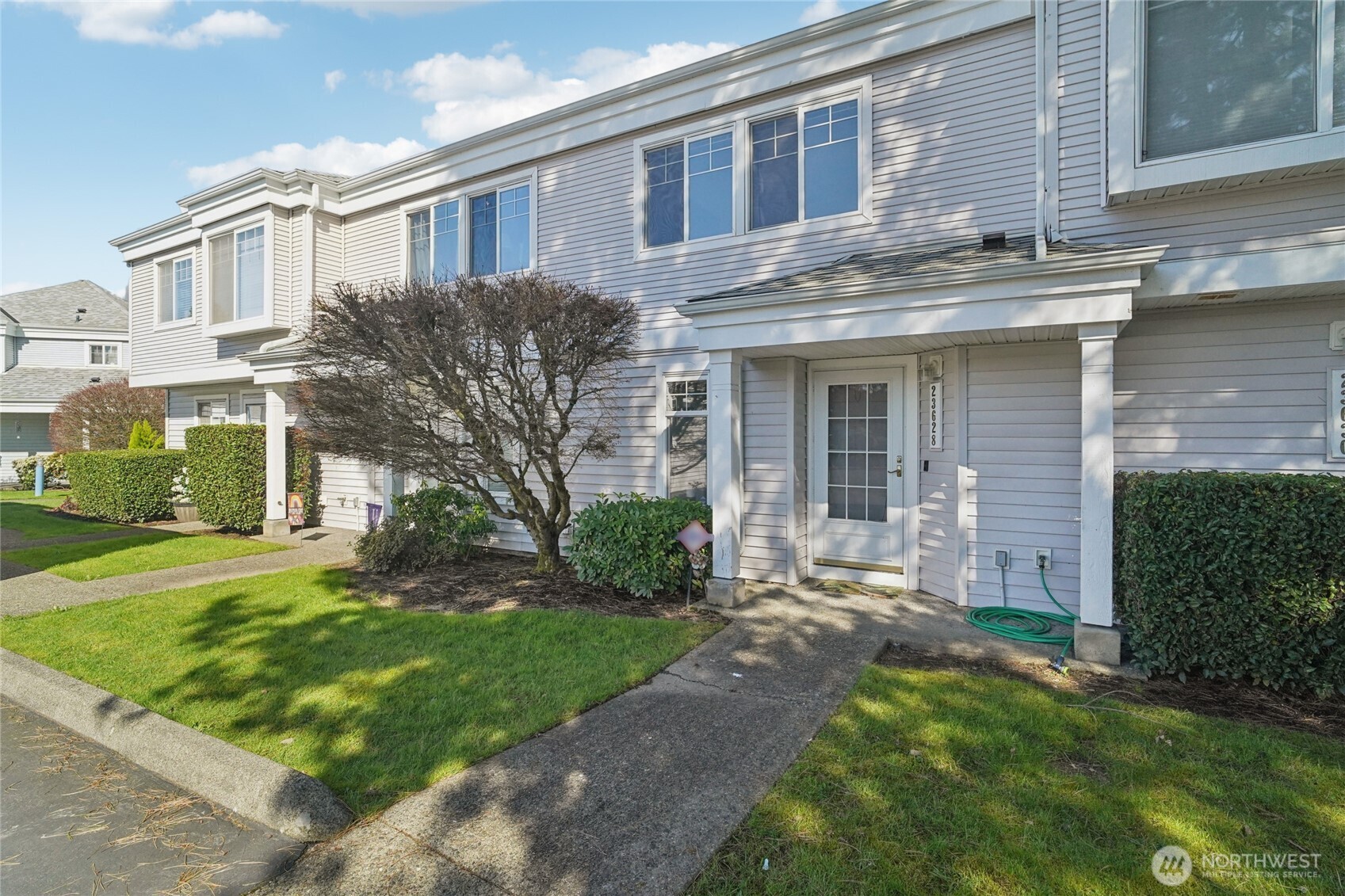 23628 55th Place South, Unit 153 Kent, WA 98032 - Photo 1 of 28 a view of a brick house with a yard plants and a large tree