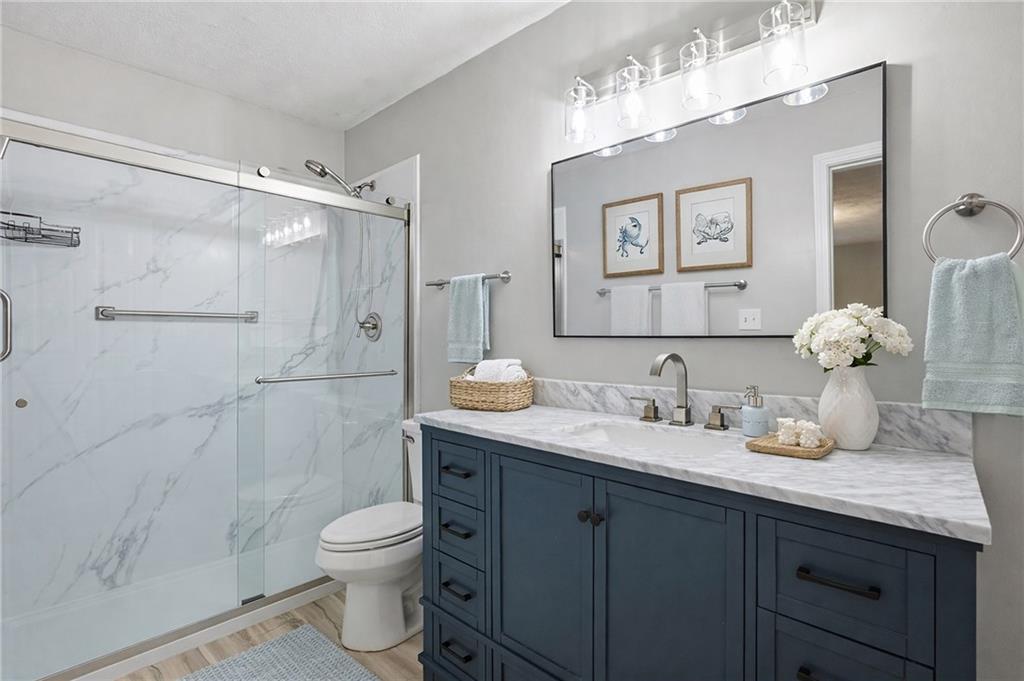 106 Berkeley Woods Drive Duluth, GA 30096 - Photo 10 of 17 a bathroom with a granite countertop sink toilet a large mirror a shower and a bathtub