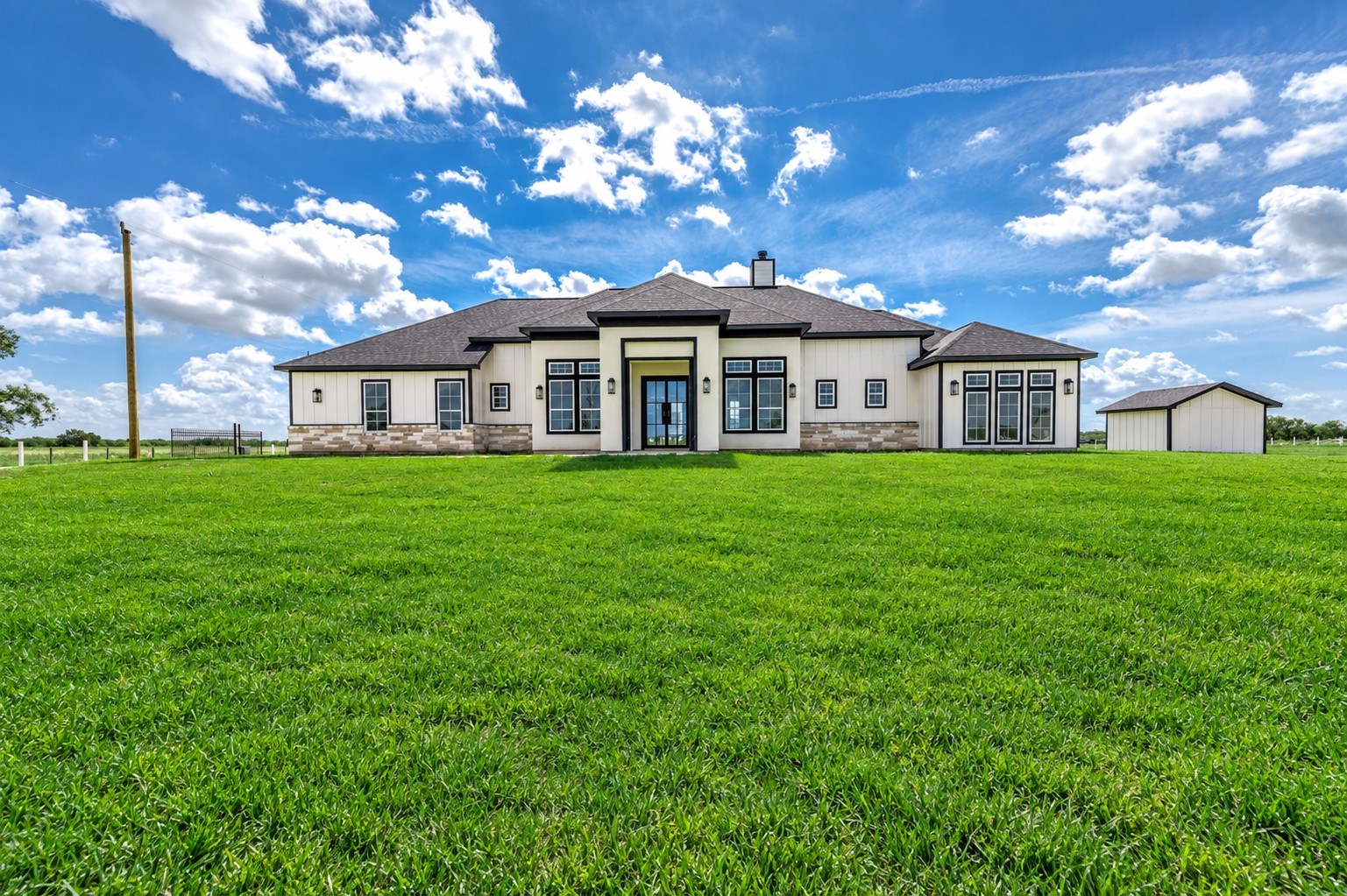 13911 Routt Point Road Needville, TX 77461 - Photo 4 of 19 Beautiful custom home with a modern exterior, stone accents, and plenty of open green space surrounding the property.