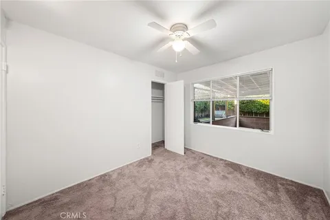 an empty room with chandelier fan and windows