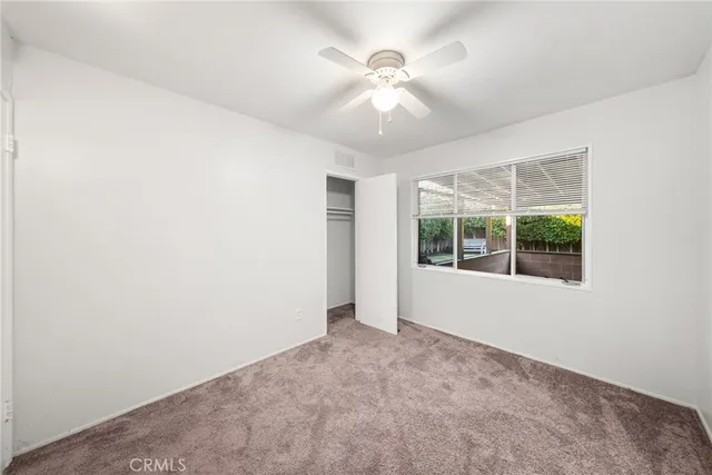an empty room with chandelier fan and windows