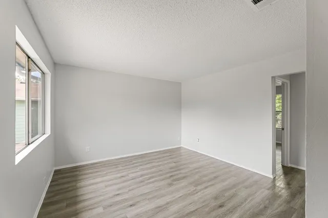 an empty room with wooden floor and windows