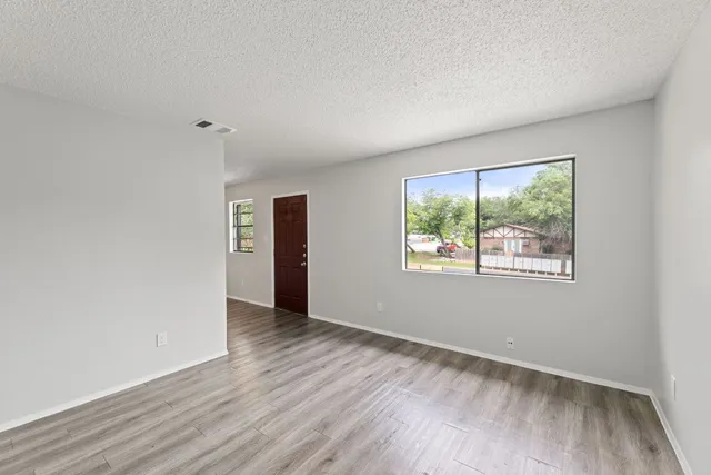 an empty room with wooden floor and windows