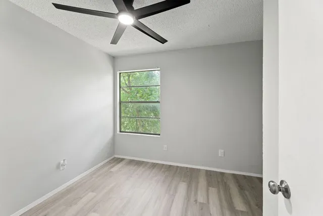 an empty room with a window and ceiling fan