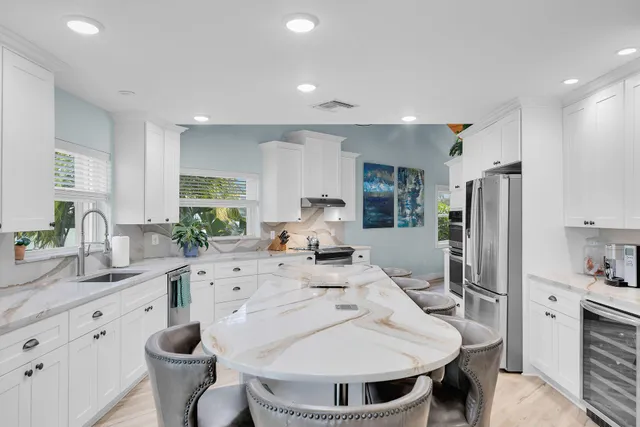 a kitchen with stainless steel appliances kitchen island granite countertop a sink cabinets and wooden floor