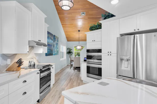 a kitchen with stainless steel appliances granite countertop a stove a sink a microwave a dining table and chairs