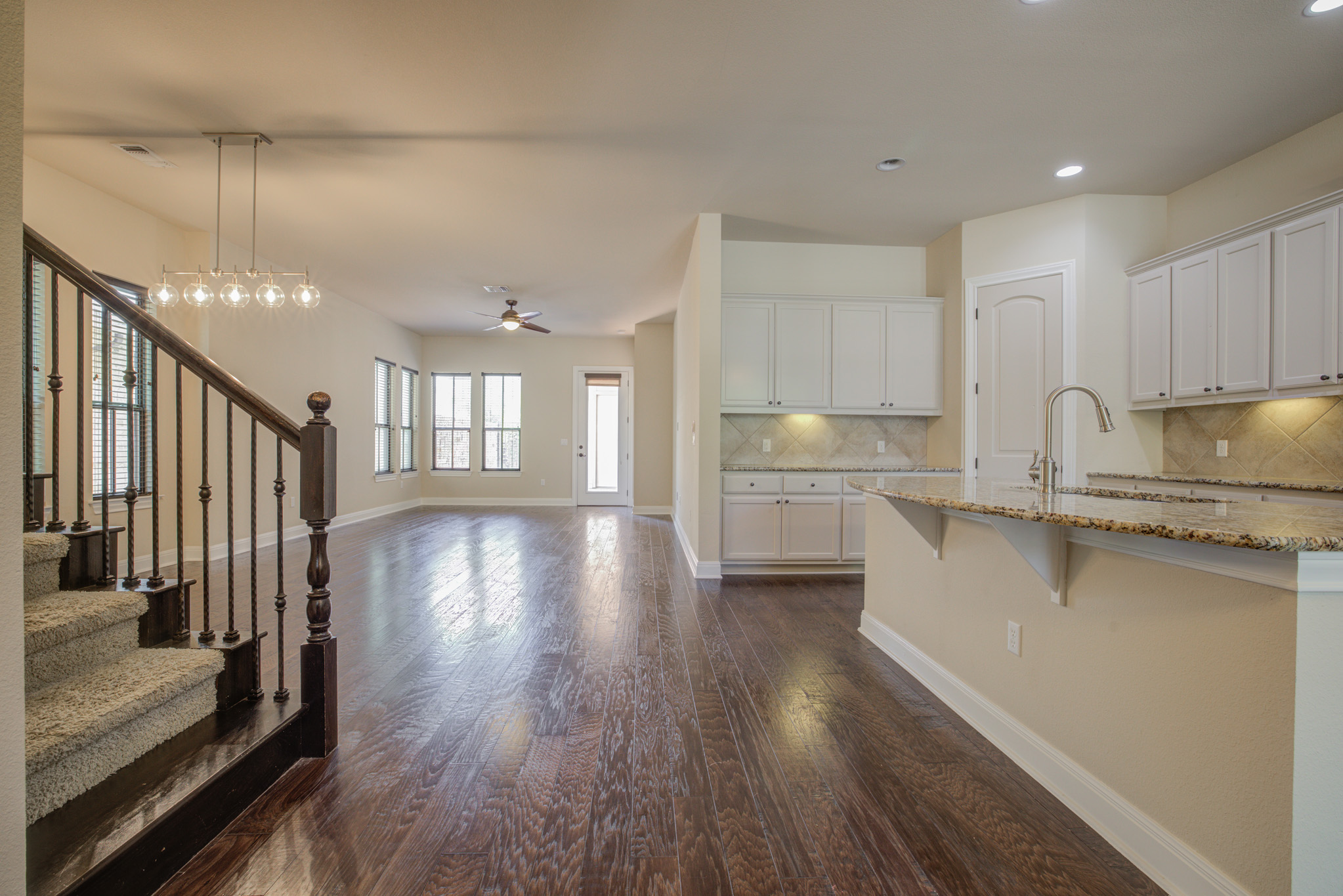 4524 Berkman Drive Austin, TX 78723 - Photo 9 of 38 Open-concept living area with dark wood-finish flooring, a contemporary linear chandelier, and a carpeted staircase with dark wood newel posts