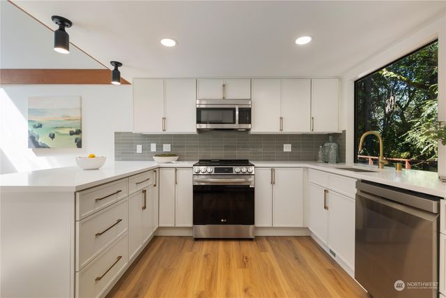 a kitchen with stainless steel appliances granite countertop a stove a sink and a microwave