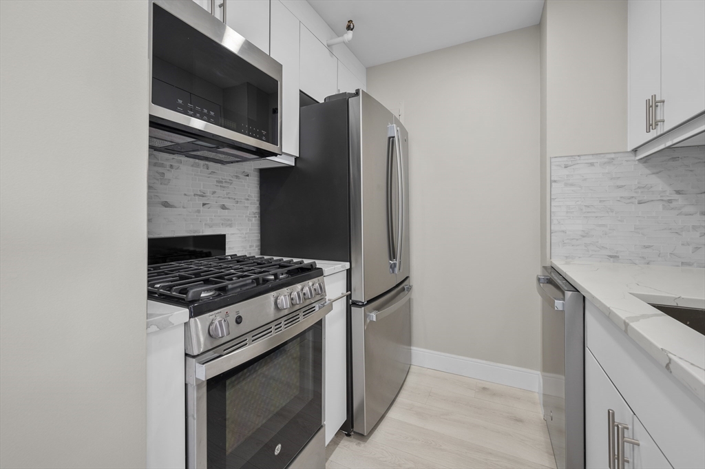 151 Tremont Street, Unit 18M Boston, MA 02111 - Photo 12 of 35 a kitchen with stainless steel appliances granite countertop a stove and a microwave with granite countertops
