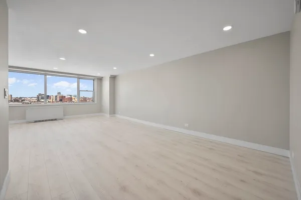 an empty room with wooden floor and natural light