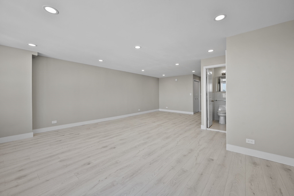 151 Tremont Street, Unit 18M Boston, MA 02111 - Photo 8 of 35 an empty room with wooden floor and natural light