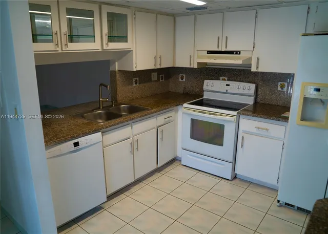 a kitchen with granite countertop white cabinets and white appliances