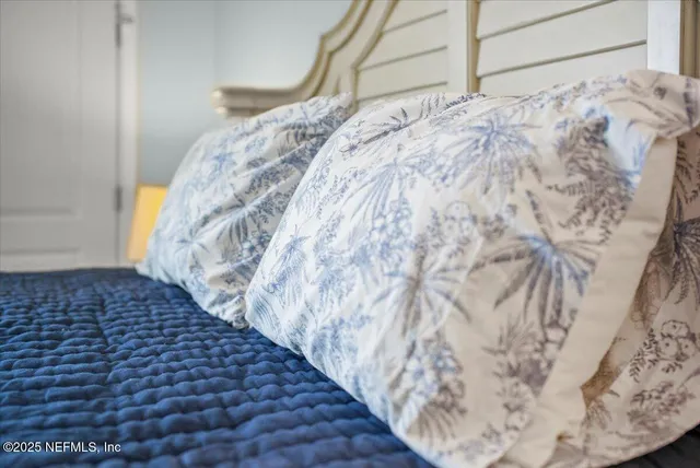 a view of a white house with a yard plants and palm trees