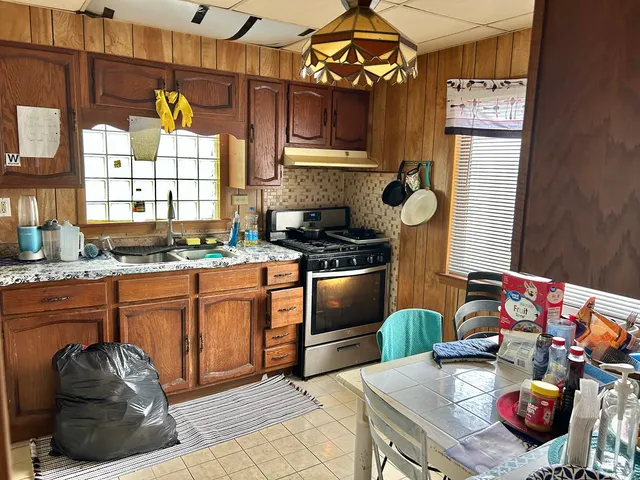 a kitchen with stainless steel appliances granite countertop a sink a stove and a wooden floor