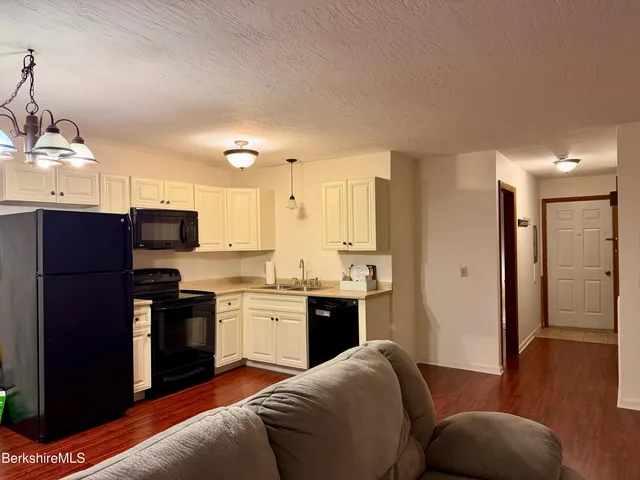 a kitchen with stainless steel appliances granite countertop a refrigerator a sink dishwasher and a stove with wooden floor