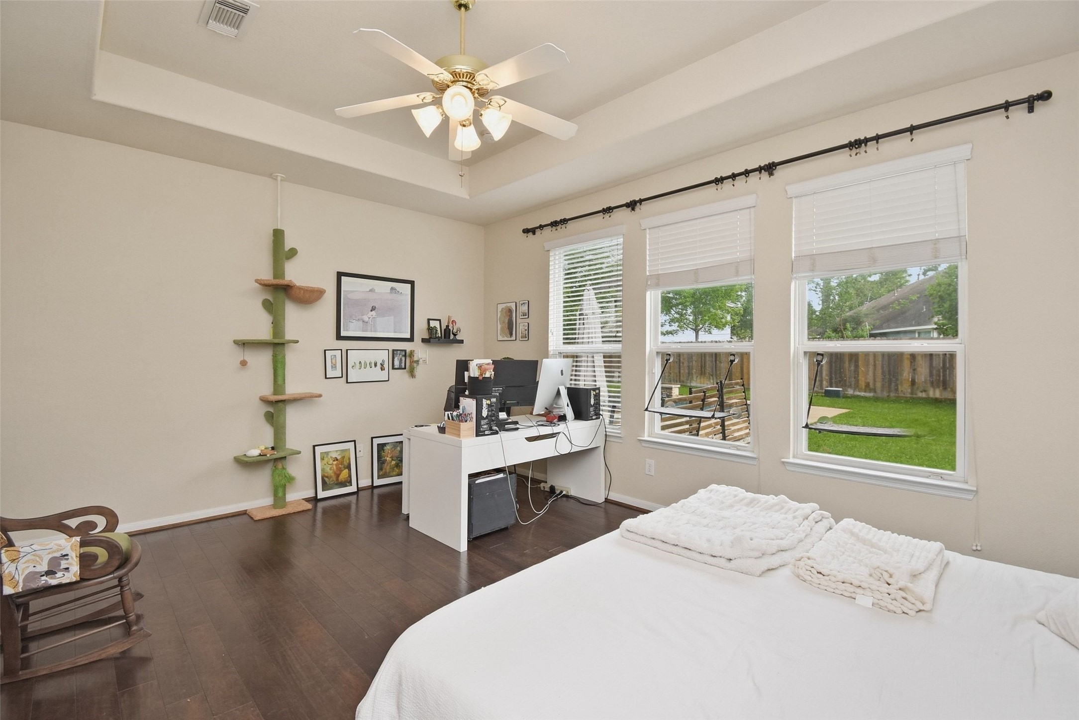 5615 Edgewood Pl Drive Spring, TX 77379 - Photo 26 of 48 Spacious first-floor primary bedroom featuring tray ceilings, rich wood flooring and large windows that fill the room with natural light, with ample space for a sitting area or workspace.
