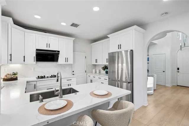 a kitchen with granite countertop a sink white cabinets and stainless steel appliances