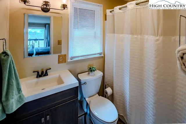 a bathroom with a sink a toilet a mirror and shower curtain