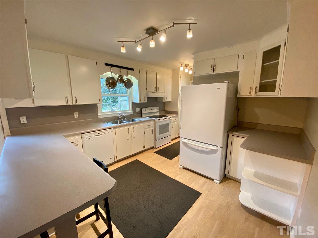 3701 Lail Court Raleigh, NC 27606 - Photo 6 of 25 a kitchen with a refrigerator a stove and white cabinets with wooden floor
