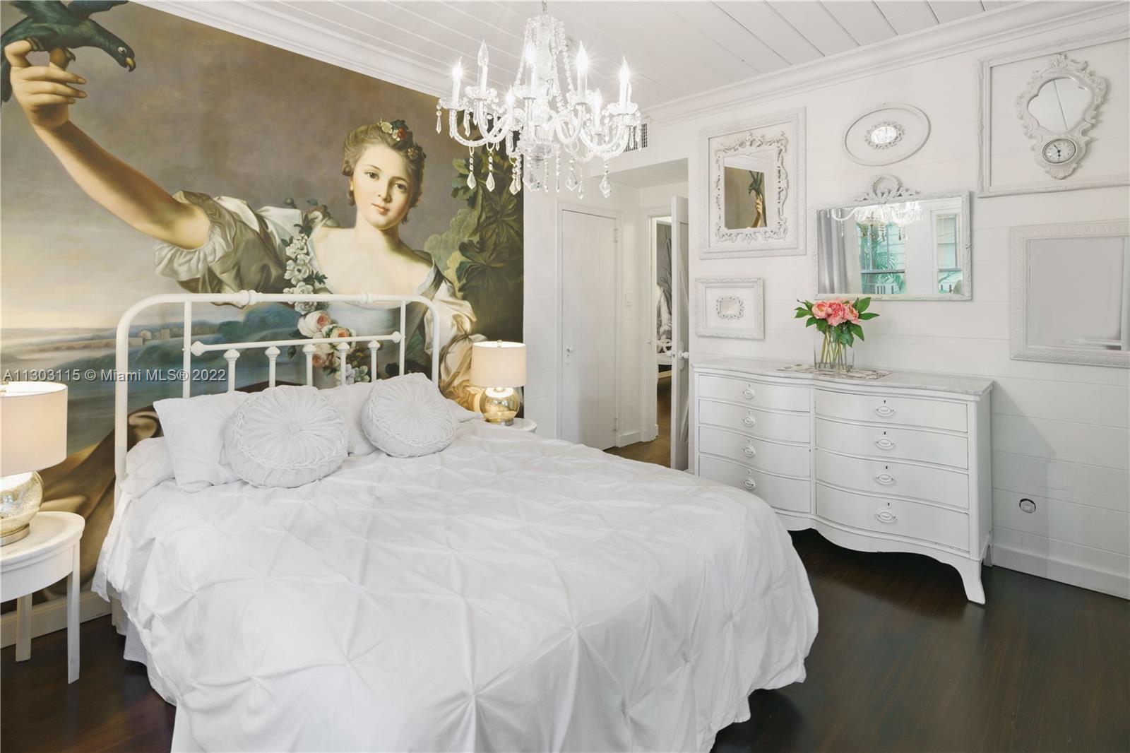 a bedroom with a bed a chandelier and dresser