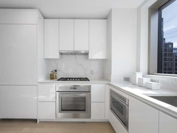 133 Seaport Boulevard, Unit 1203 Boston, MA 02210 - Photo 5 of 5 a kitchen with granite countertop white cabinets and white appliances