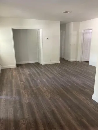 a view of an empty room with wooden floor and closet