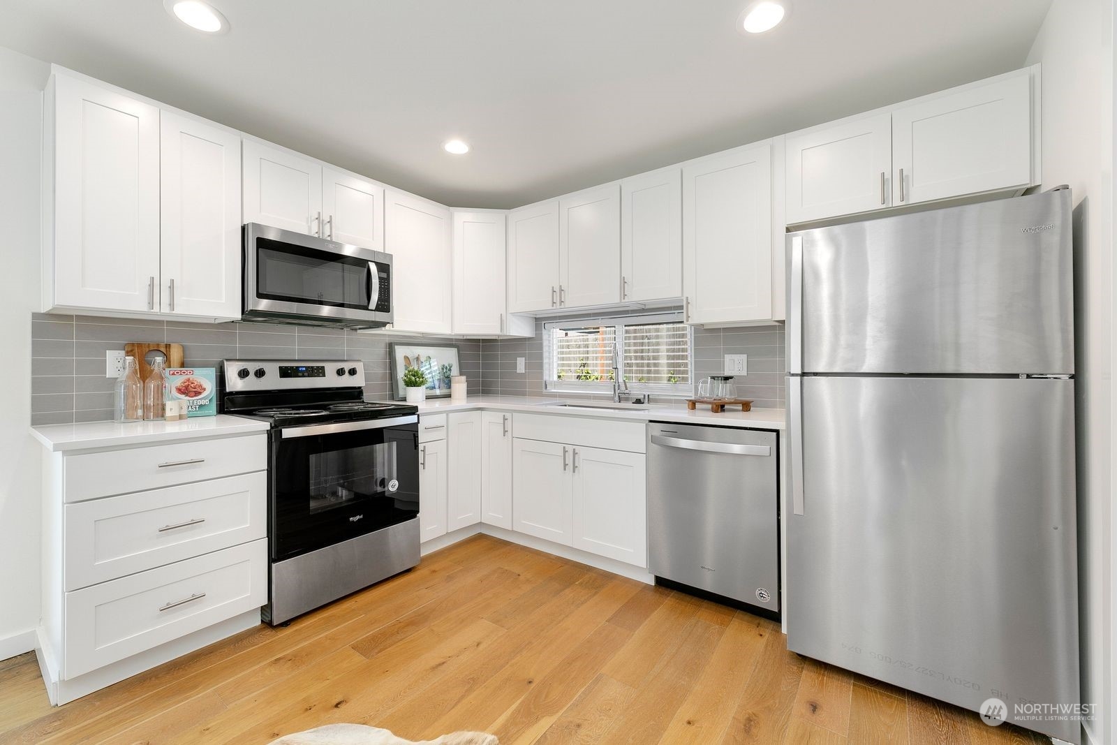 4246 South Graham Street Seattle, WA 98118 - Photo 4 of 21 a kitchen with white cabinets and stainless steel appliances