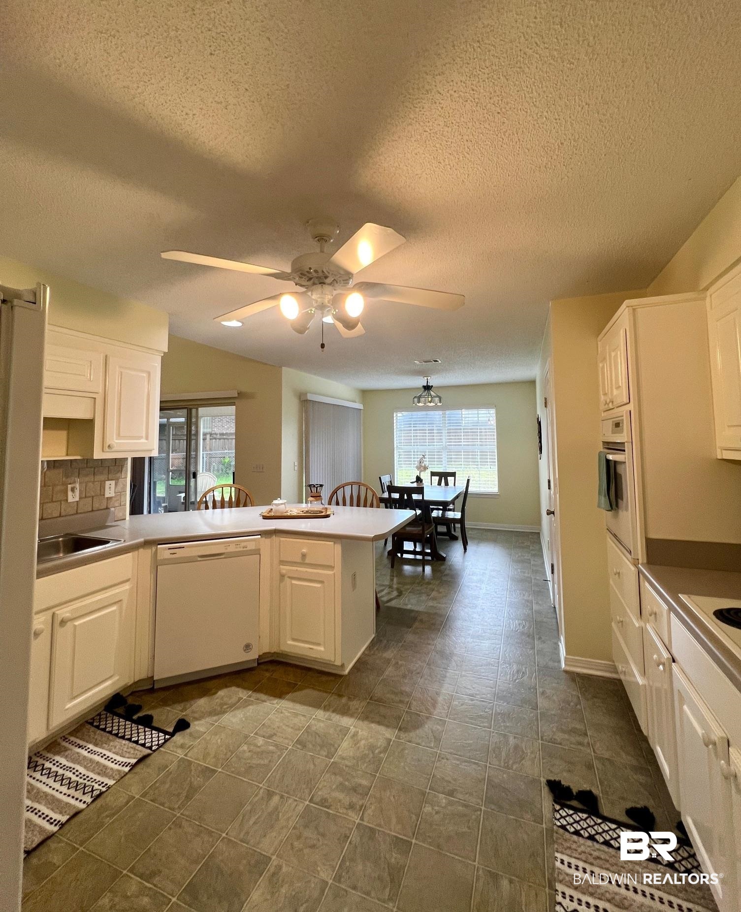 2204 Club House Drive Lillian, AL 36549 - Photo 8 of 38 Kitchen featuring white appliances, a textured ceiling, a peninsula, and white cabinets