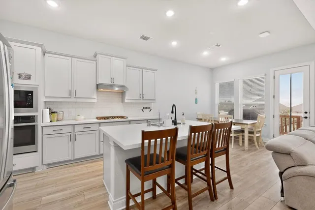 a kitchen with stainless steel appliances granite countertop a table chairs sink and cabinets