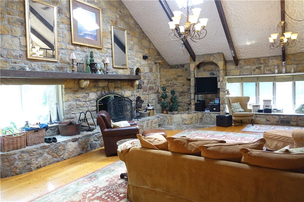 227 Meridian Road Butler, PA 16001 - Photo 12 of 25 First floor family room with stone fireplace, cathedral ceiling, hardwood flooring, and glass doors which lead to the inground pool.