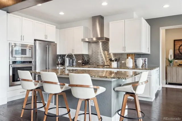 a kitchen with stainless steel appliances a dining table chairs refrigerator and sink