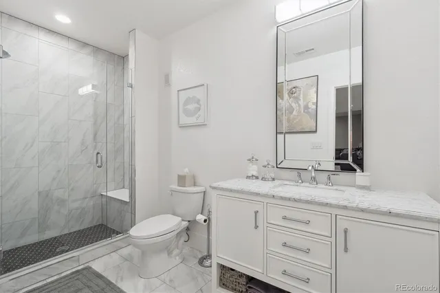 a bathroom with a granite countertop sink toilet a mirror and shower