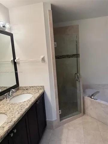 a bathroom with a granite countertop sink a mirror and shower